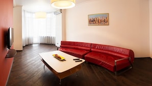 A modern living room with a red leather sofa, a wooden coffee table, and a flat-screen TV mounted on the wall. - Apart Kiev Zlatoustovskaya 50-1 (Kyiv)