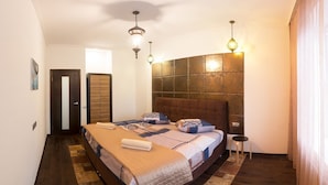 A bedroom with a large bed, two bedside tables, a headboard, and a small stool. - Apart Kiev Zlatoustovskaya 50-1 (Kyiv)