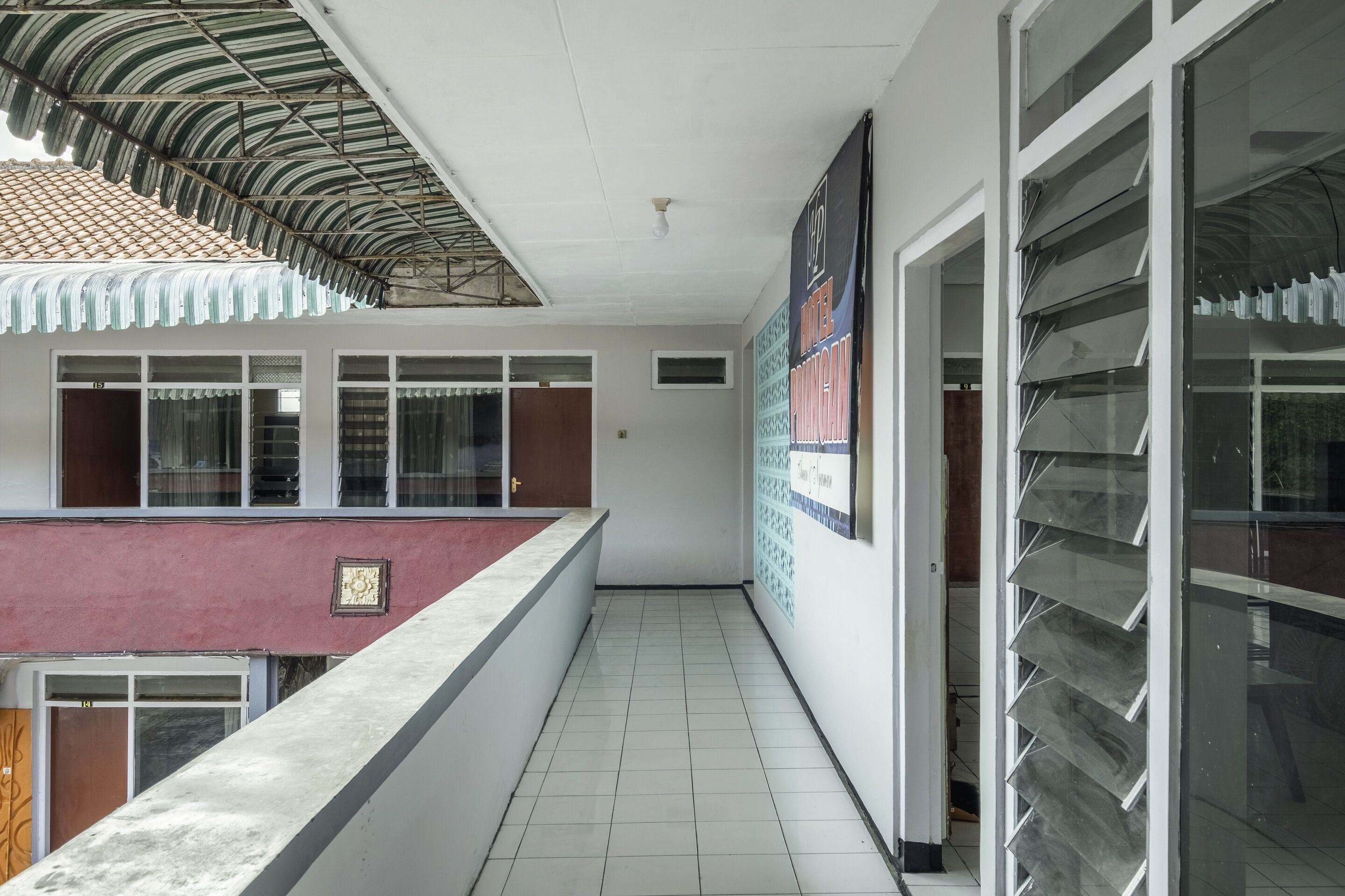 A corridor with tiled flooring, a red and white wall, and a metal awning.