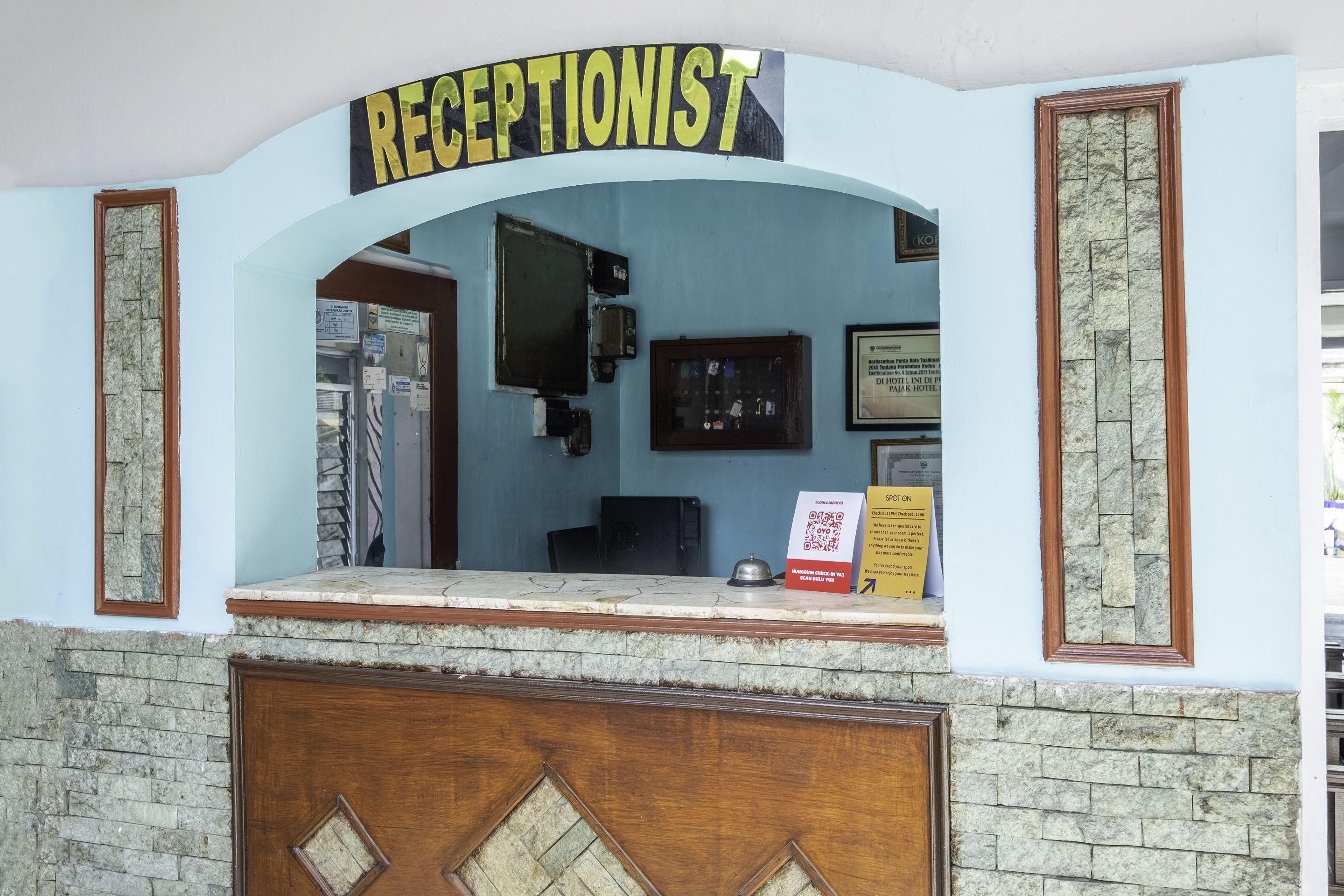 A reception area with a reception desk, a sign reading "RECEPTIONIST," and a framed certificate on the wall.
