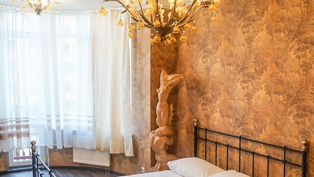 A bedroom with a large bed, a chandelier, and a decorative wall. - Apart Kiev Zlatoustovskaya 50-2 (Kyiv)