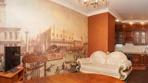 A spacious living room with a large mural of a historical cityscape, a classic sofa, a wooden dining table, and a modern kitchen in the background. - Apart Kiev Zlatoustovskaya 50-2 (Kyiv)