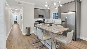 A modern kitchen with a central island, stainless steel appliances, and a chandelier. - Bright 3BR Mid-City home with private patio & fenced yard. Steps to streetcar, near FQ & Superdome (New Orleans)