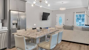 A modern kitchen with a marble countertop, stainless steel appliances, and a dining area with a sofa and chairs. - Bright 3BR Mid-City home with private patio & fenced yard. Steps to streetcar, near FQ & Superdome (New Orleans)