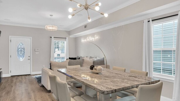 A modern dining area with a marble table, cushioned chairs, and a chandelier. - Bright 3BR Mid-City home with private patio & fenced yard. Steps to streetcar, near FQ & Superdome (New Orleans)