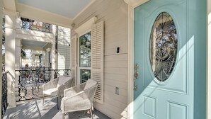 A porch with wicker chairs and a blue door with a decorative glass panel. - Bright 3BR Mid-City home with private patio & fenced yard. Steps to streetcar, near FQ & Superdome (New Orleans)