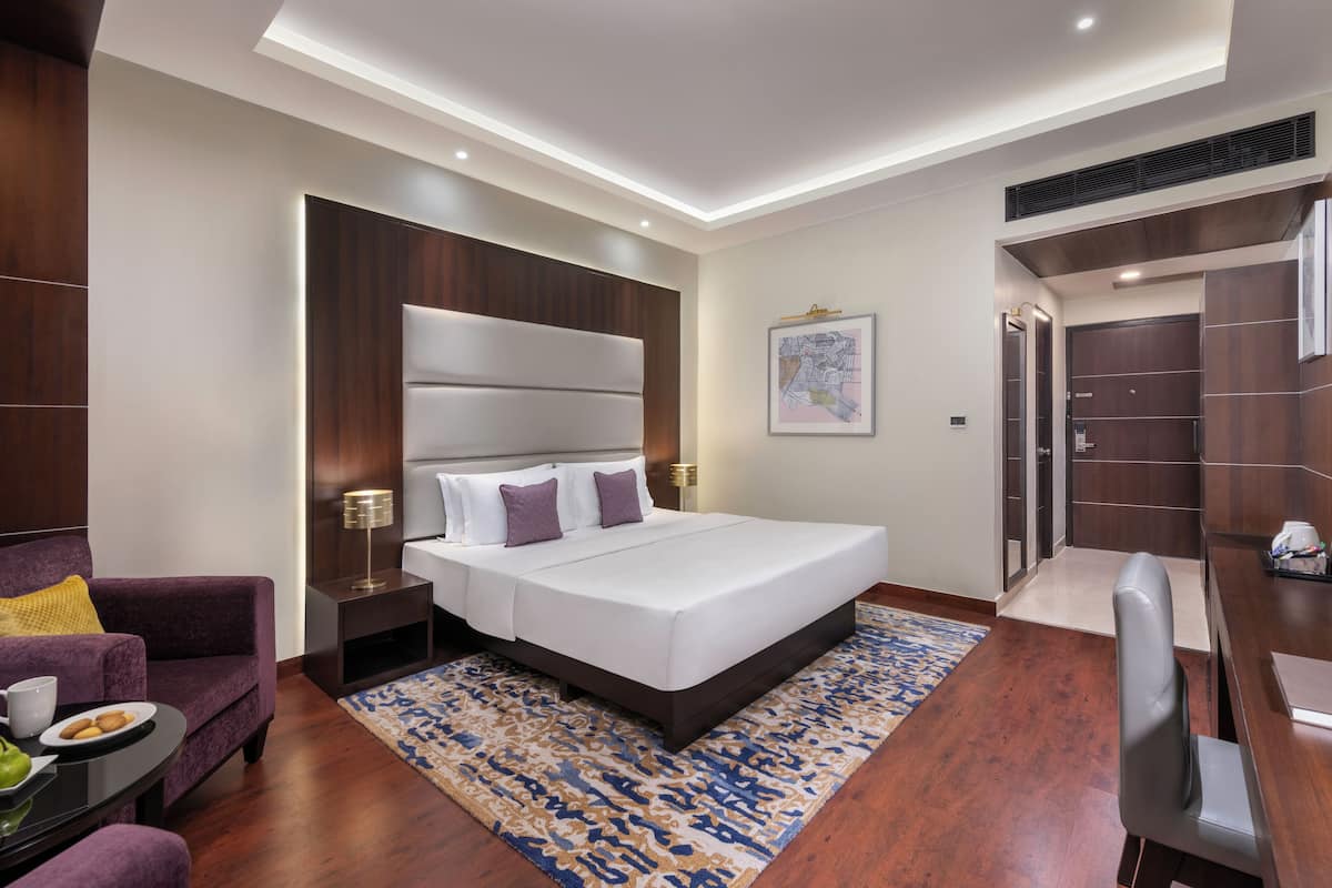 Una habitación de hotel moderna con una cama grande, un escritorio, una silla y un sofá.