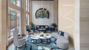 Un hall d’entrée moderne agrémenté d’une grande fresque murale, de coins salon et d’un tapis à motifs.