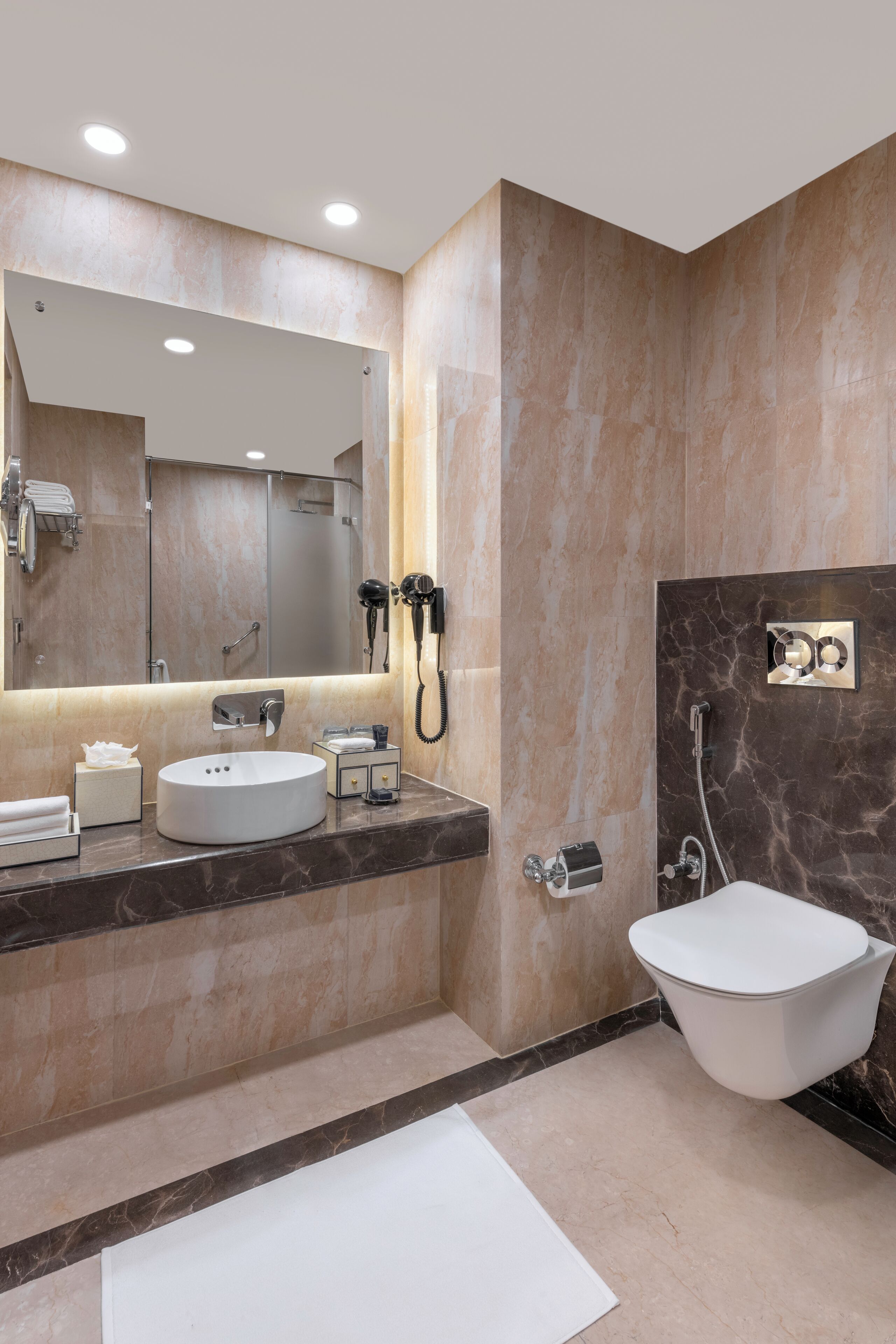 Un baño moderno con un espejo grande, un lavabo redondo, inodoro y ducha.