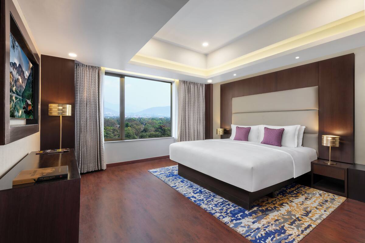 Una habitación de hotel moderna con una cama grande, un escritorio y vistas a las montañas.