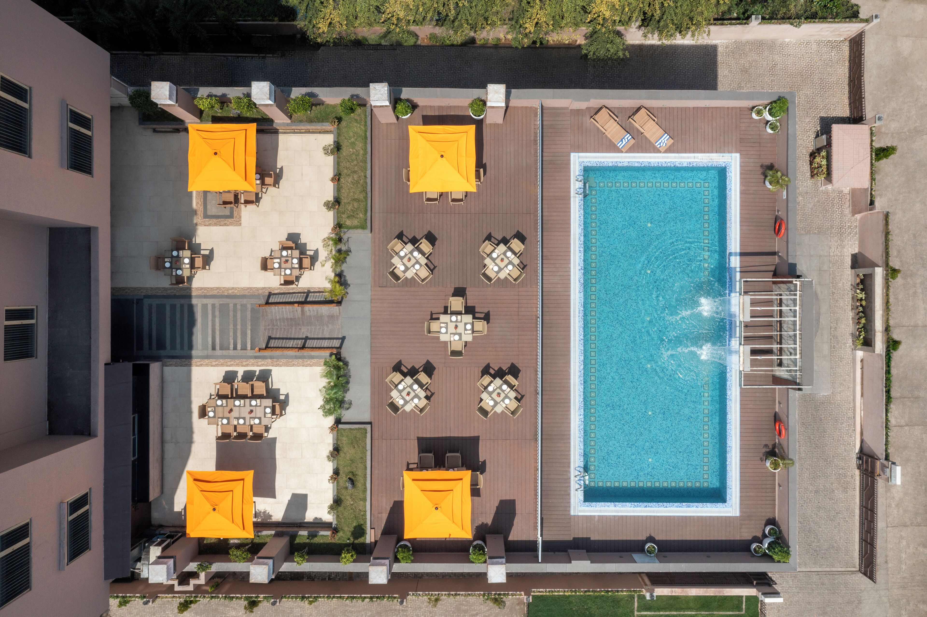 An aerial view of a rooftop pool area with multiple seating arrangements and a central swimming pool.