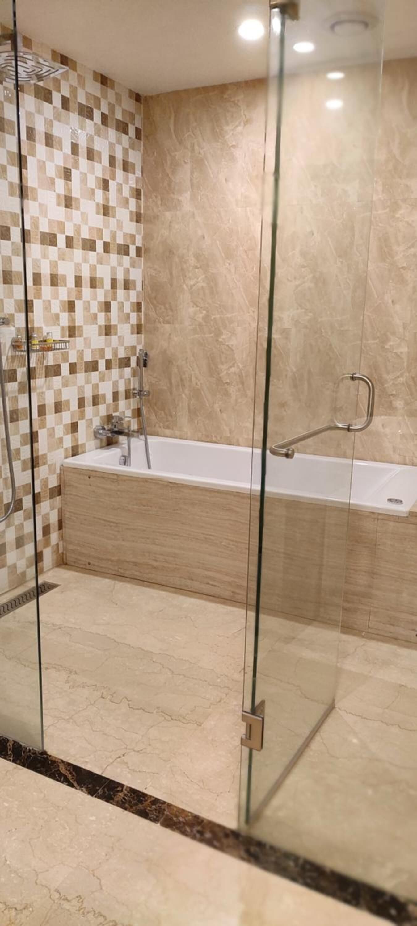 A modern bathroom with a glass-enclosed shower, a freestanding bathtub, and a checkered tile wall.