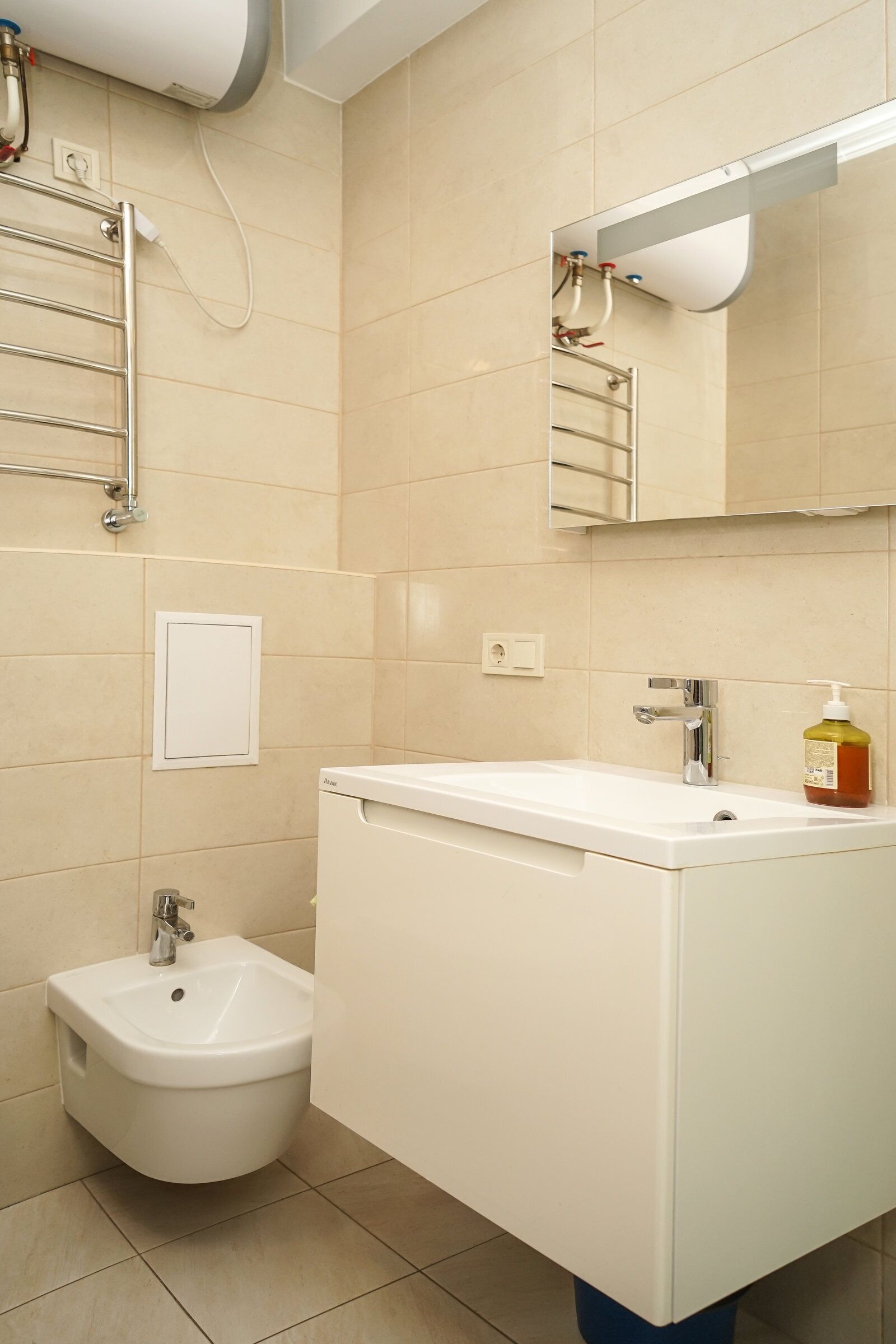 A modern bathroom with a white sink, bidet, and a mirror above the sink.