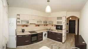 Cozinha compacta com geladeira, forno, micro-ondas e máquina de lavar.