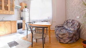 Ett kompakt bostadsutrymme med kök, matplats och sittgrupp.