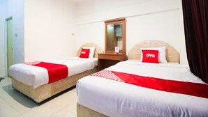 A hotel room with two beds, each with a red and white bedspread and matching pillows. There is a wooden nightstand with a mirror between the beds. - OYO 1905 Davonsa  Homestay Syariah (Pekanbaru)