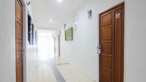 A hallway with wooden doors, a tiled floor, and a painting on the wall. - OYO 1905 Davonsa  Homestay Syariah (Pekanbaru)