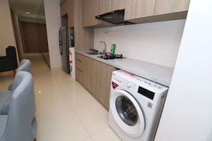 Enjoy cooking in this well-equipped kitchen with a washing machine, stainless steel sink, and range hood.