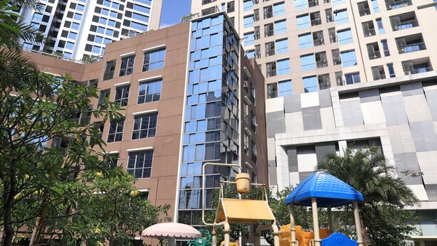 Zona de juegos infantiles con un tobogán y estructura para escalar, rodeada de edificios altos.