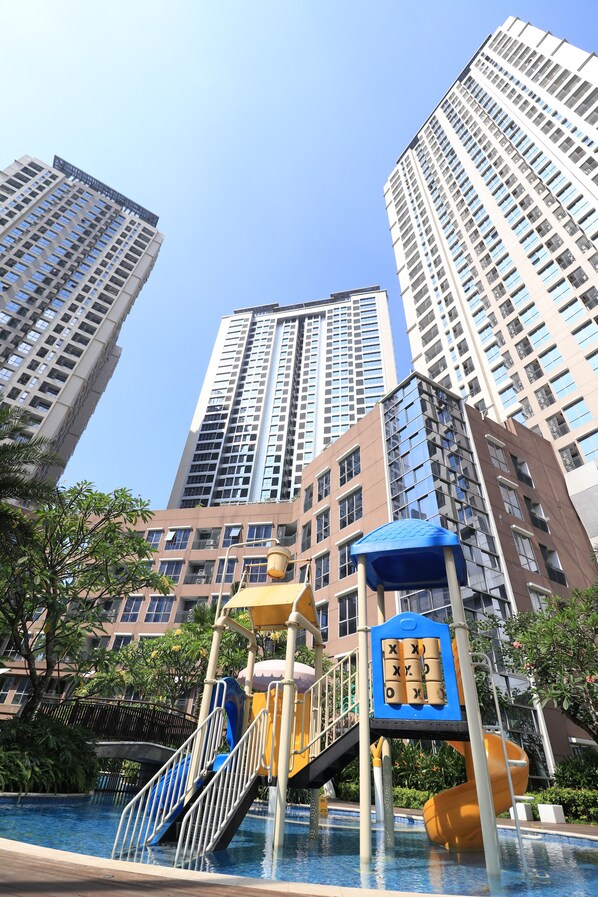 A high-rise building complex with a swimming pool and playground equipment.