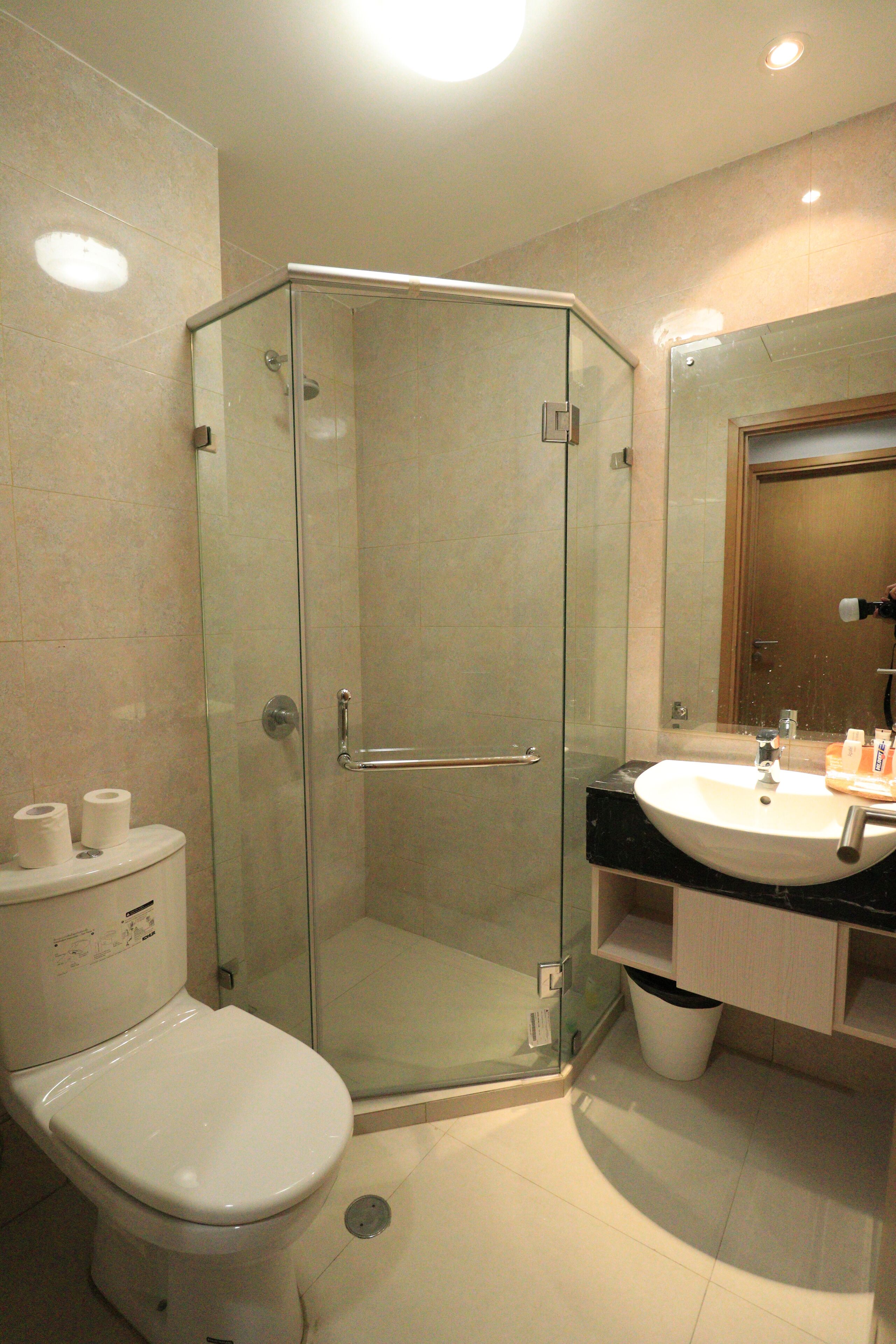 A modern bathroom with a glass-enclosed shower, a white toilet, and a sink with a mirror above it.