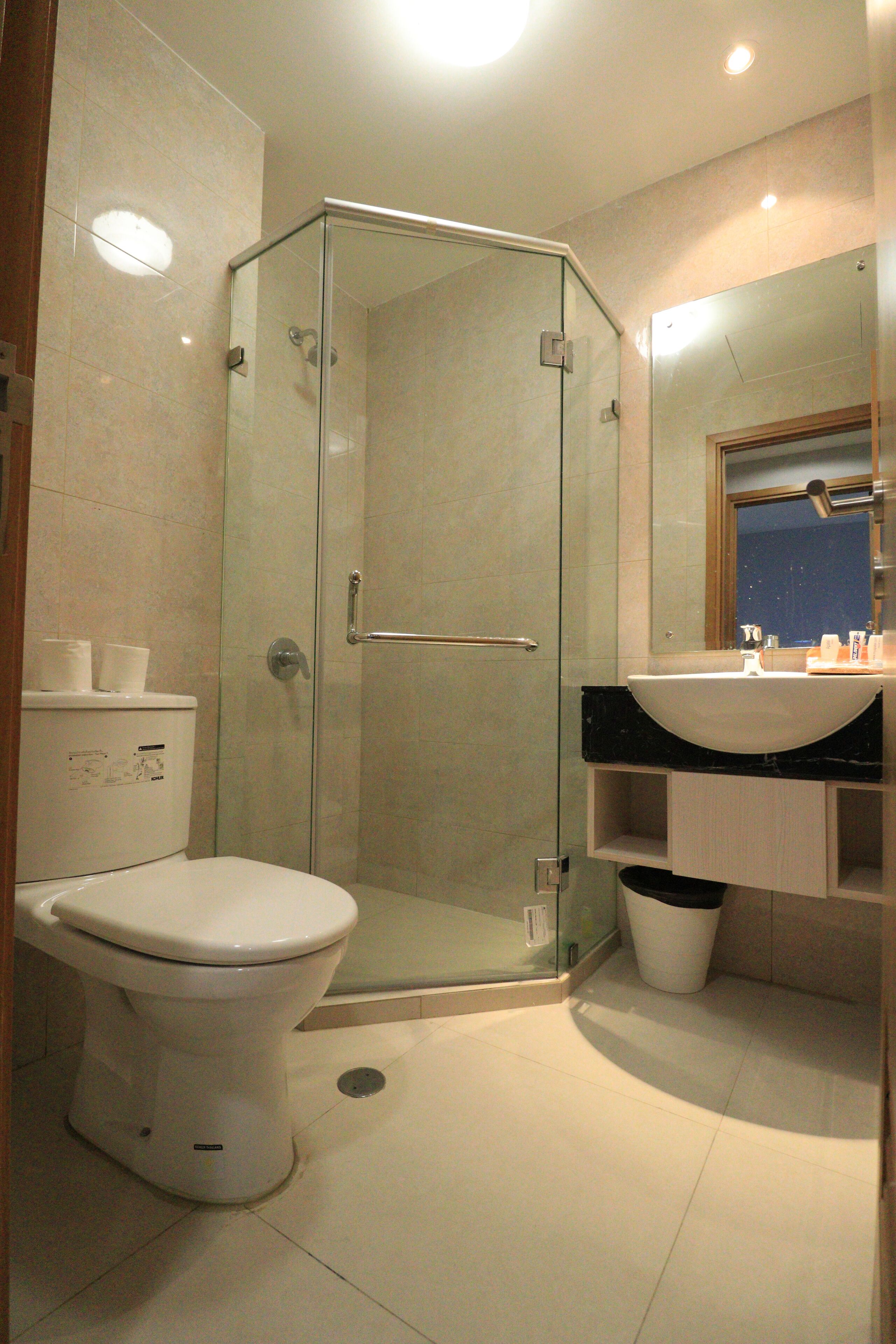 Ein modernes Badezimmer mit einer Duschkabine aus Glas, einer weißen Toilette und einem Waschbecken mit Spiegel darüber.