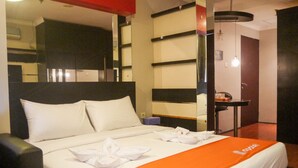 A hotel room with a bed, a nightstand, a mirror, and a small table with a chair.