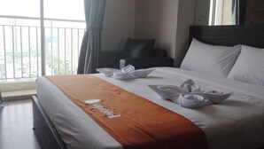 A hotel room with a bed, a window with curtains, a view of buildings, and a name tag on the bed.
