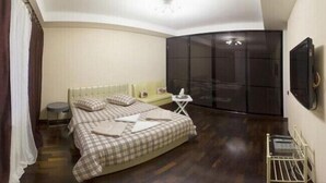 Ein Schlafzimmer mit einem Bett, einem kleinen Tisch, einer Couch und einem an der Wand befestigten Fernseher.