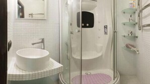 Ein Badezimmer mit einem weißen Waschbecken, einer Duschkabine und einer rosa Fußmatte.