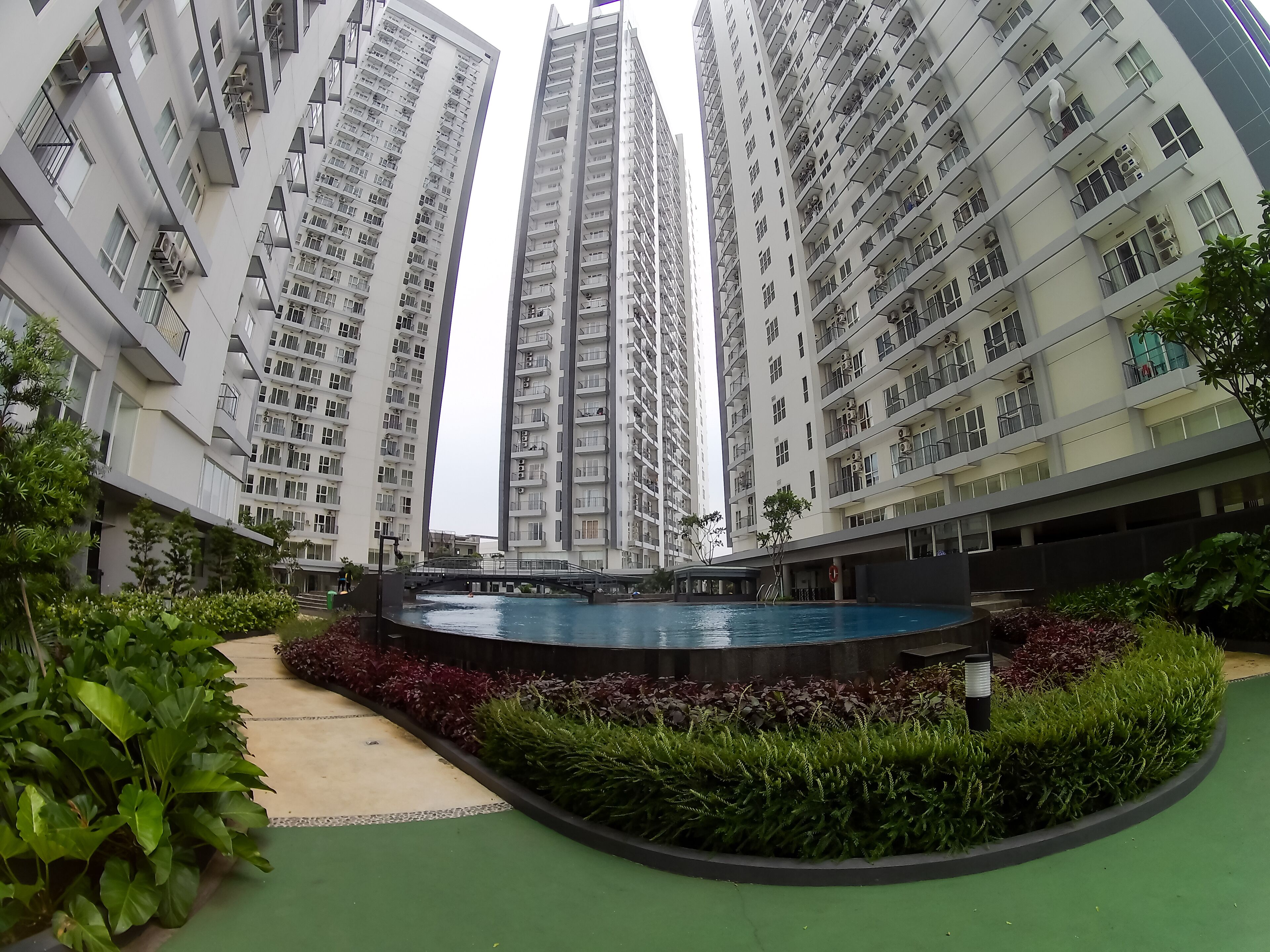 Un complexe résidentiel moderne comprenant plusieurs immeubles à étages, une cour intérieure avec une piscine et des espaces verts environnants.
