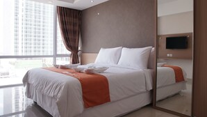 Quarto de hotel moderno com uma cama grande, televisão na parede e vista para a cidade pela janela.