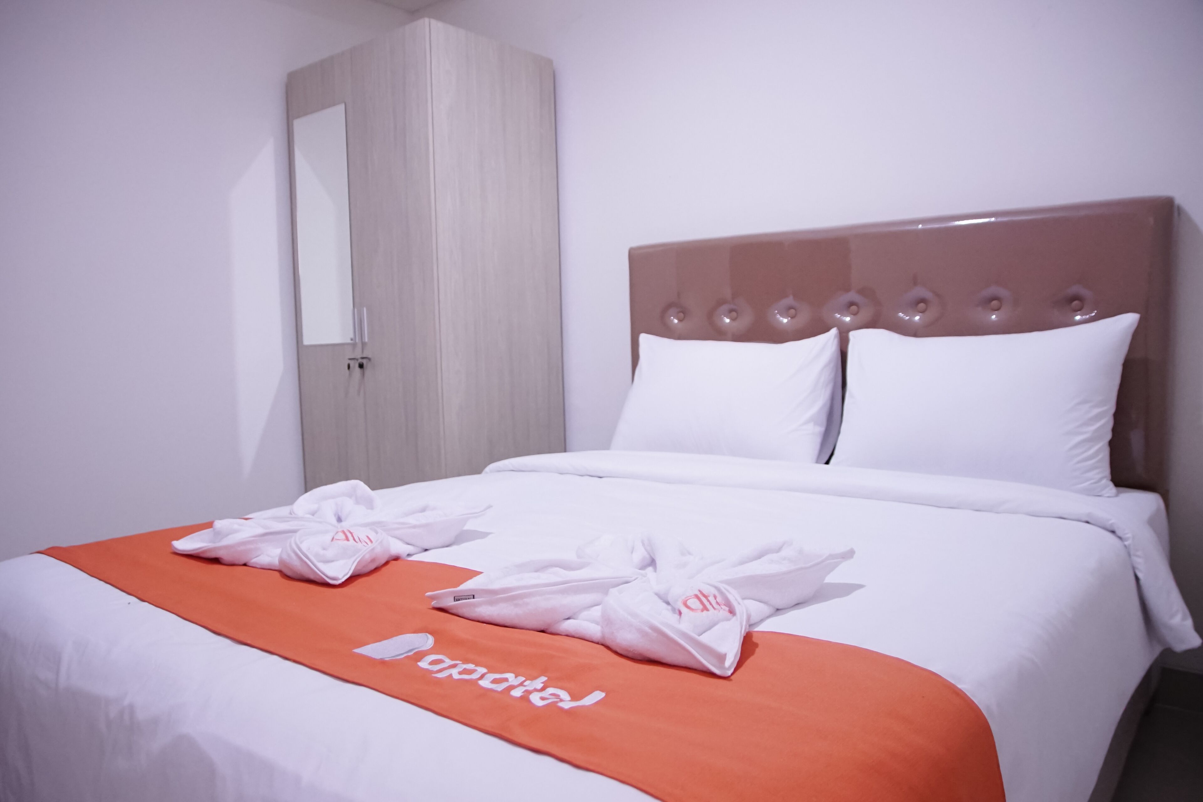 A hotel room with a bed, a wardrobe, and a mirror.