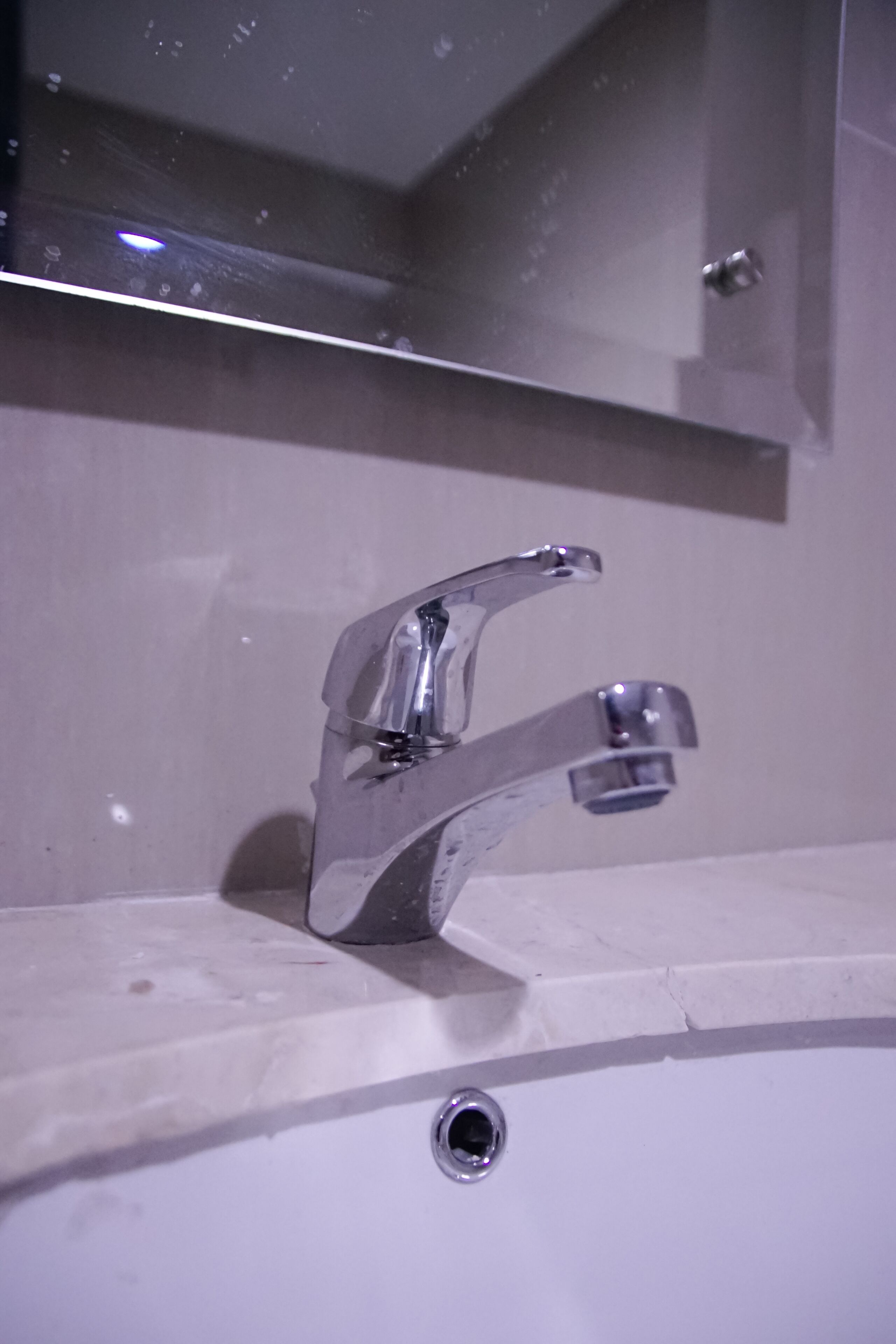 Ein Badezimmer mit einem chromfarbenen Wasserhahn und einem Spiegel darüber.