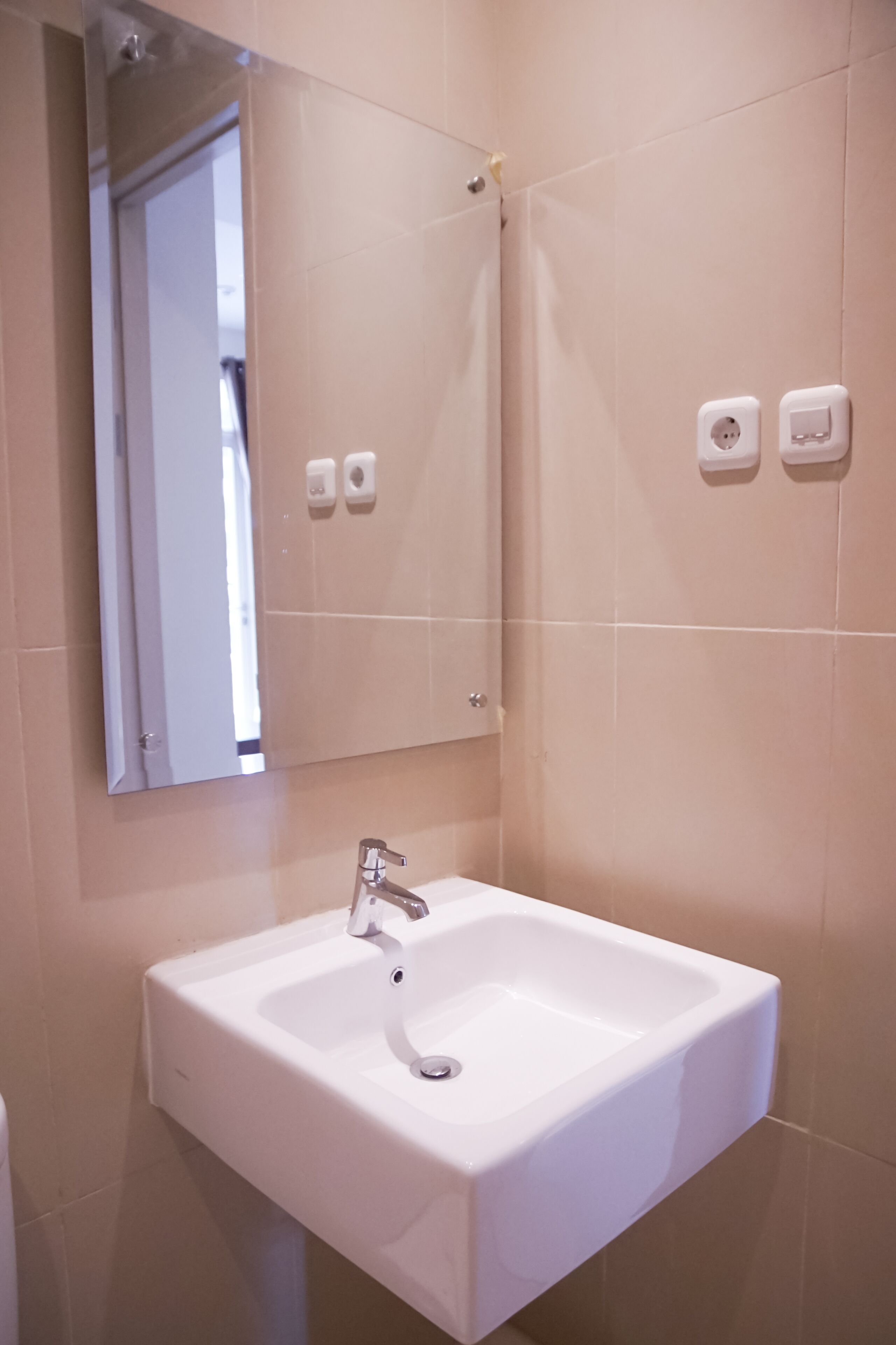 A bathroom with a white sink, a mirror, and two wall-mounted soap dispensers.