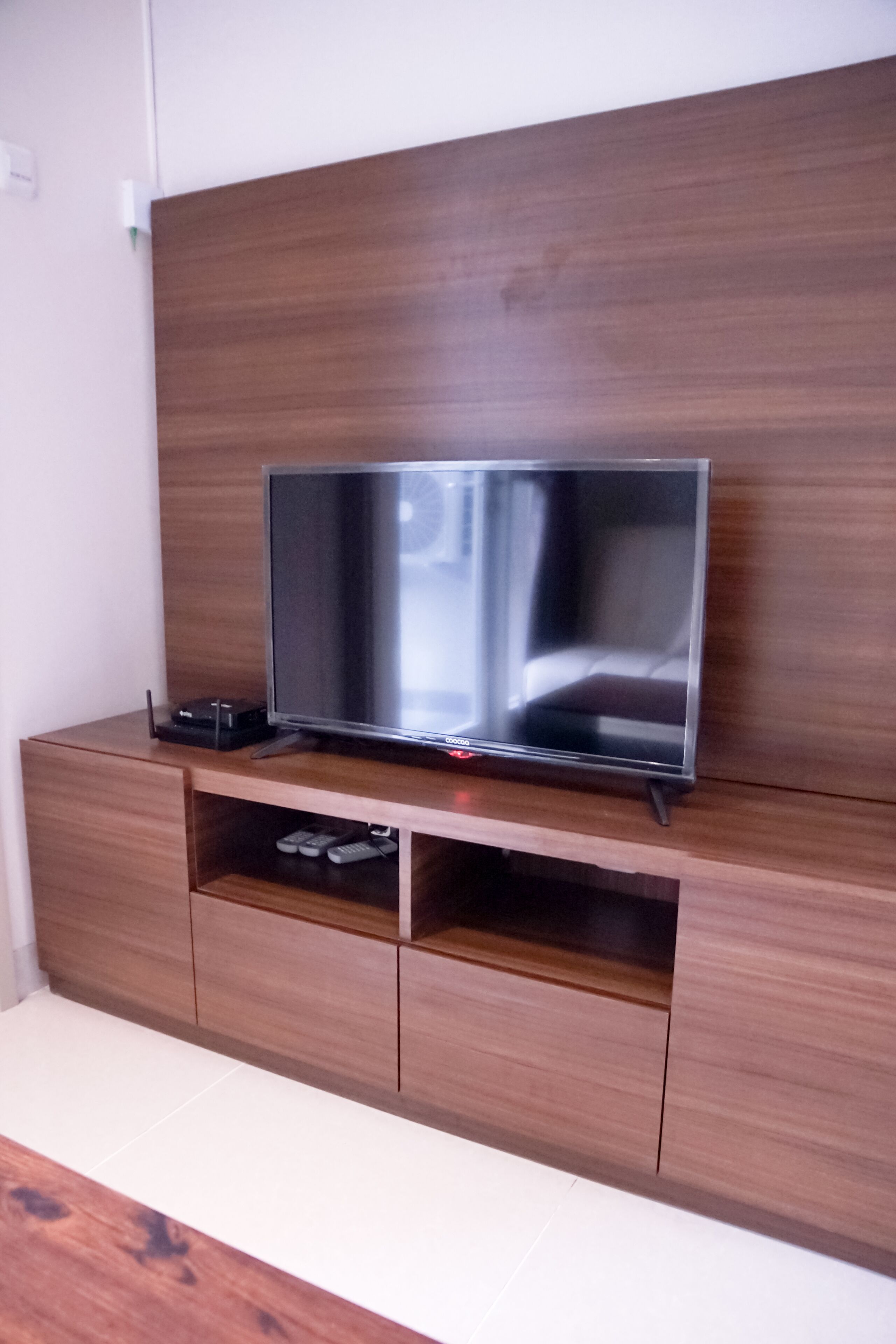A flat-screen TV on a wooden TV stand with a shelf below.