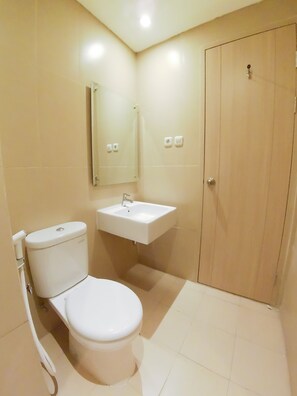 A small, clean bathroom with a toilet, sink, and mirror.