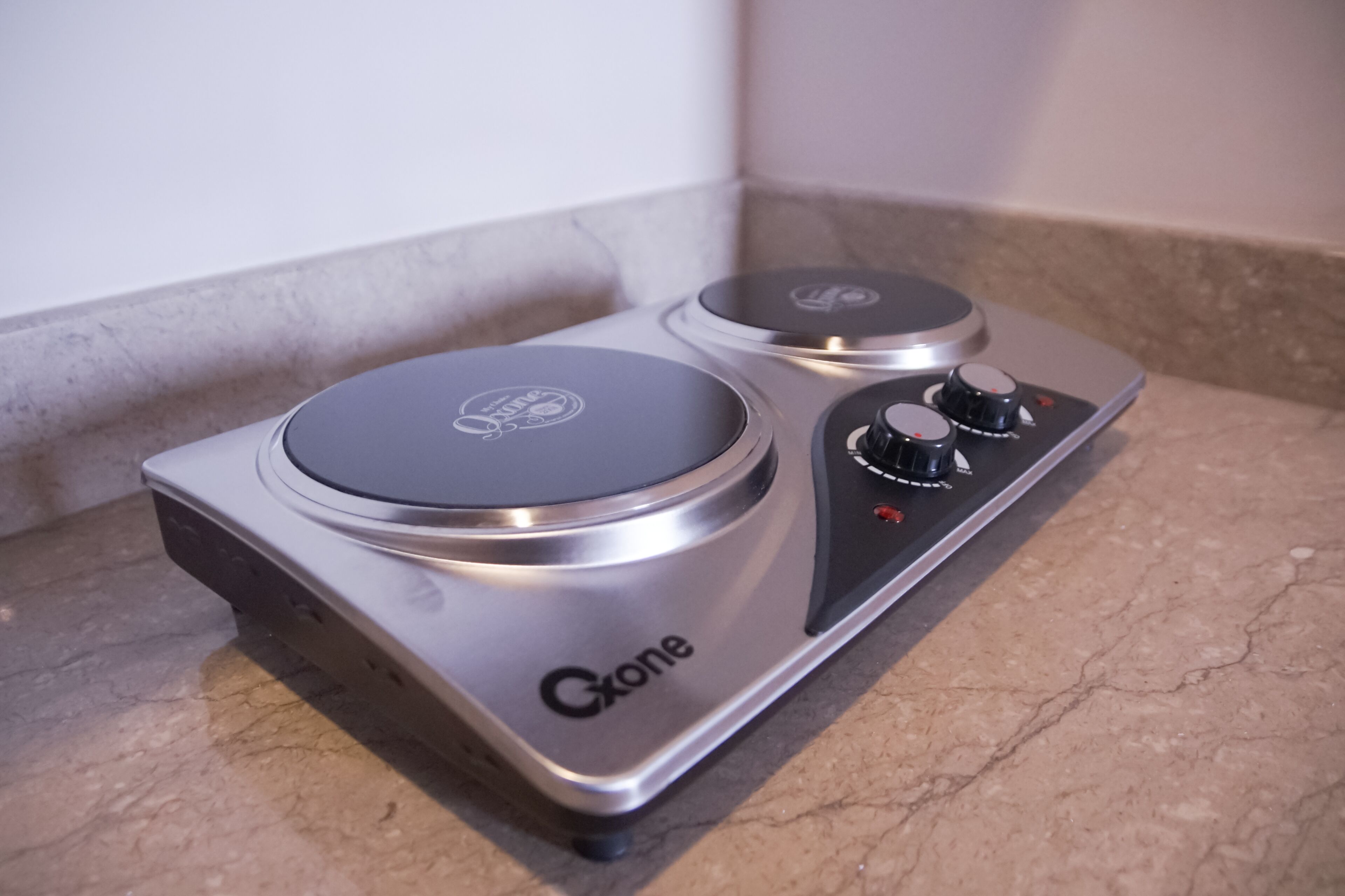 A gas stove with two burners and knobs, labeled "Gxone," on a countertop.