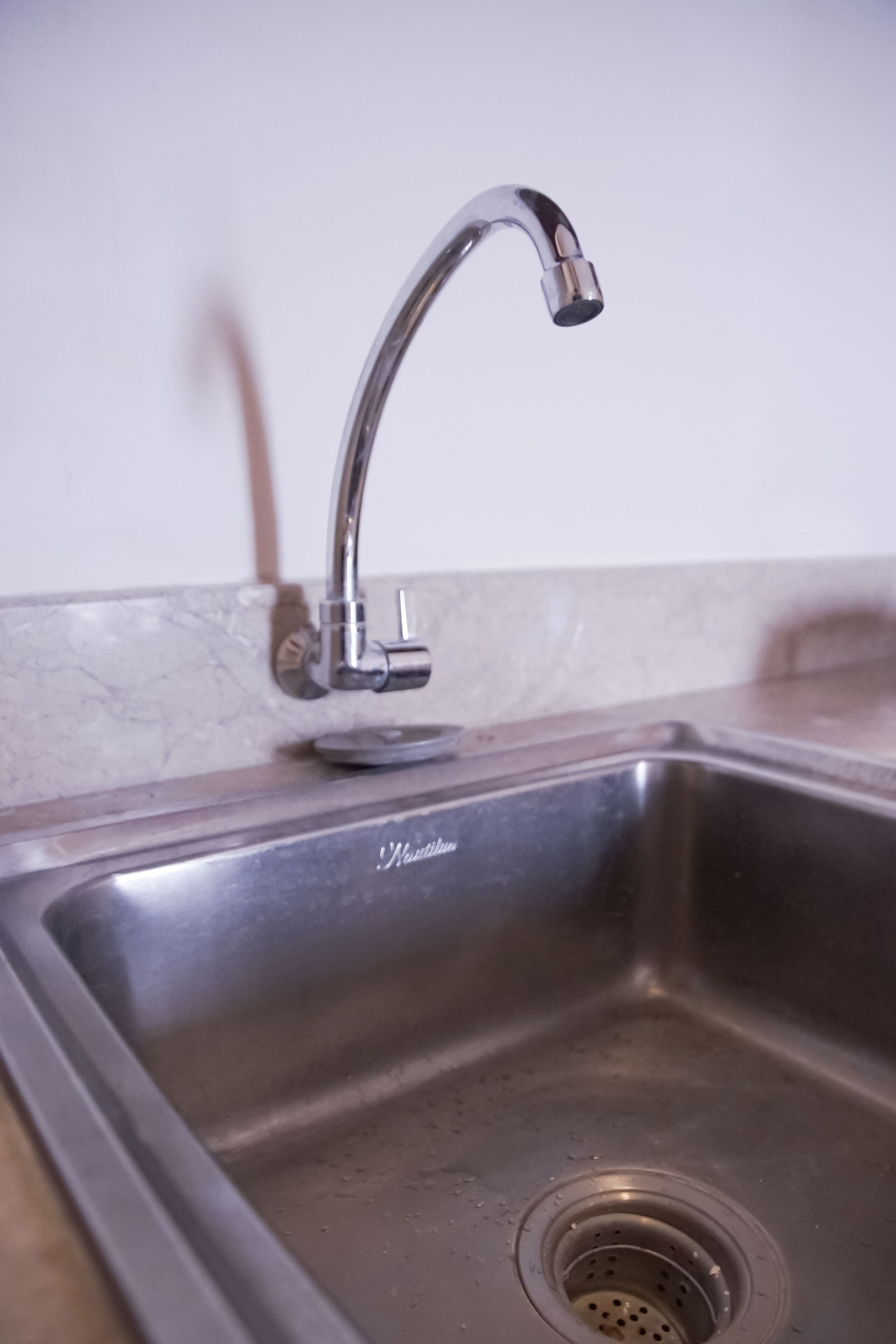 Un évier de cuisine en acier inoxydable, doté d’un seul robinet et d’un drain.