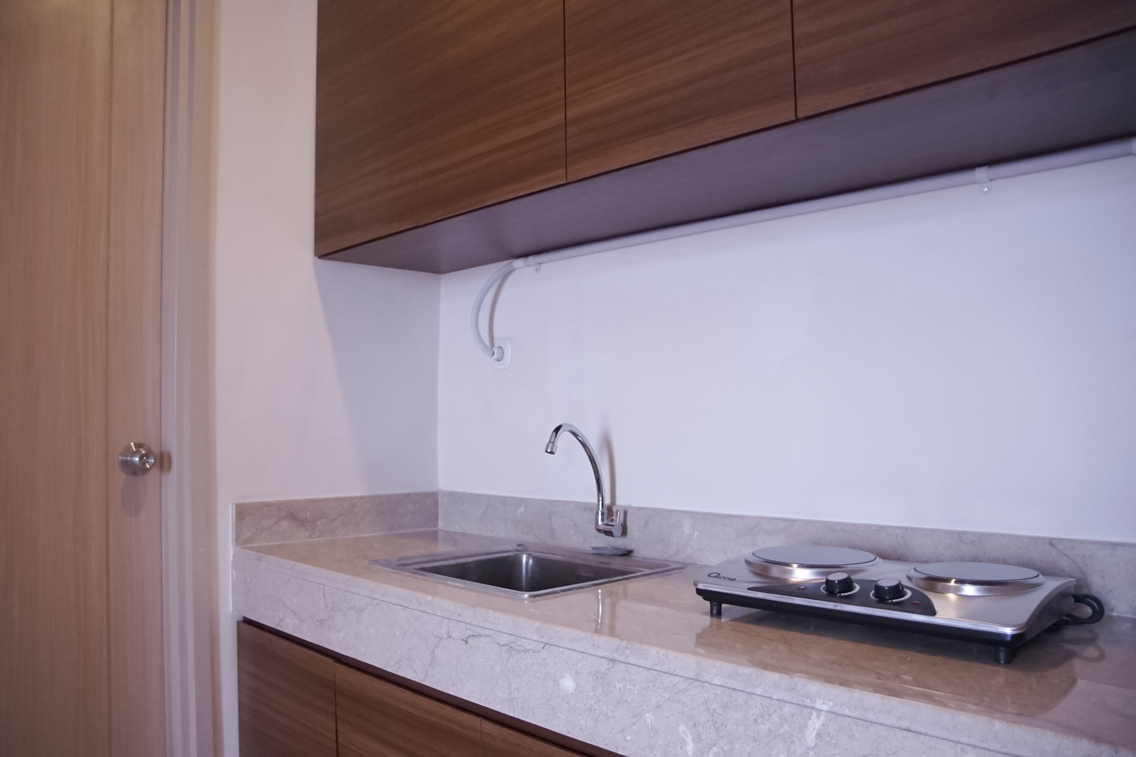 Een keuken met een spoelbak van roestvrij staal, een gasfornuis en houten kastjes.