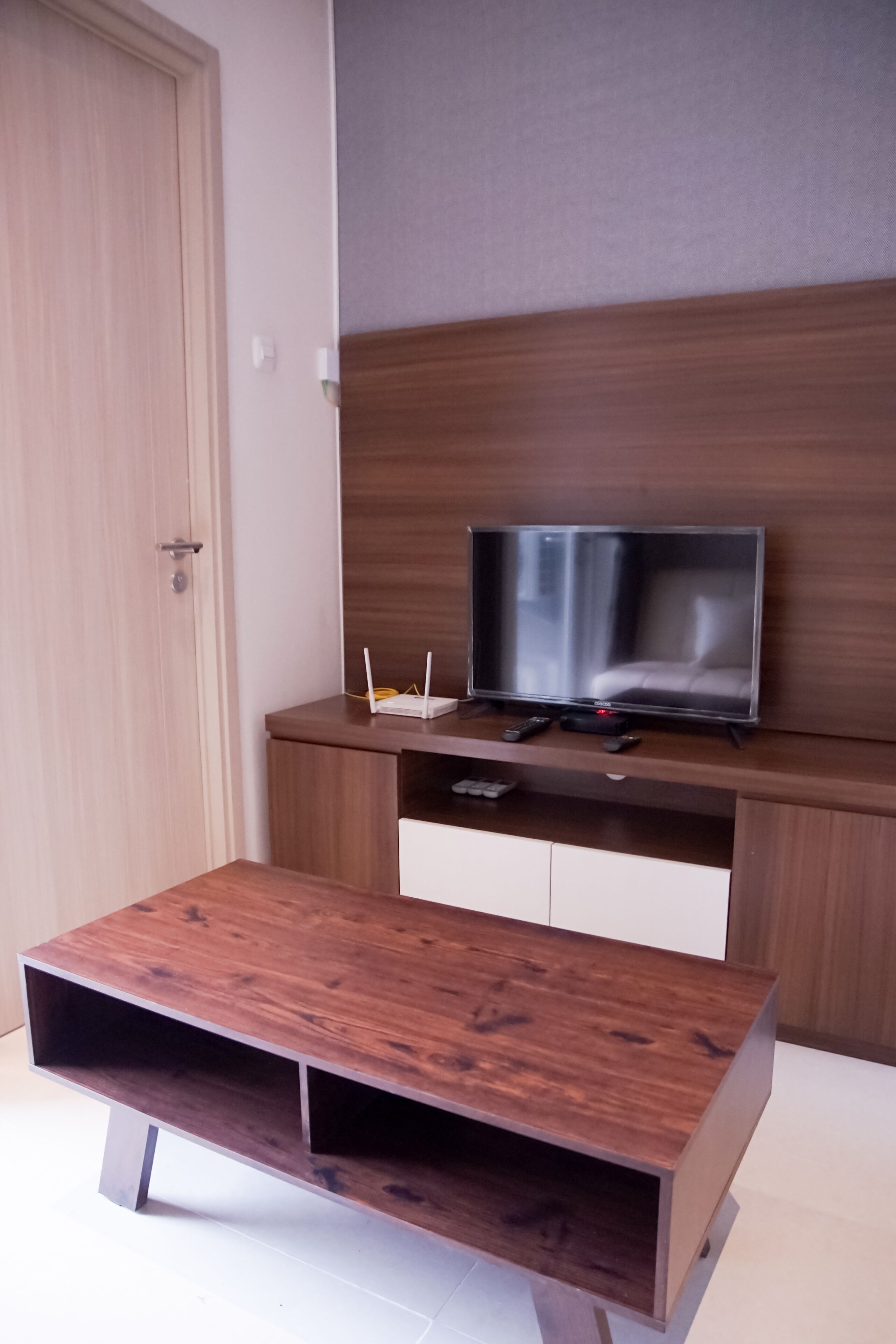 A modern room with a wooden TV stand, a flat-screen TV, and a small table.