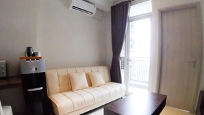 A living room with a sofa, a coffee machine, and a table. - Apatel Elpis Residences 09B01 (Jakarta)