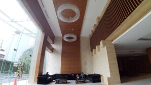 A modern lobby with a high ceiling, large chandeliers, and a seating area with sofas and a coffee table. - Apatel Elpis Residences 09B01 (Jakarta)