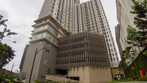 A modern high-rise building with a unique angular design, featuring multiple balconies and a mix of glass and concrete materials. - Apatel Elpis Residences 09B01 (Jakarta)