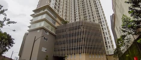 A modern high-rise building with a unique angular design, featuring multiple balconies and a mix of glass and concrete materials.