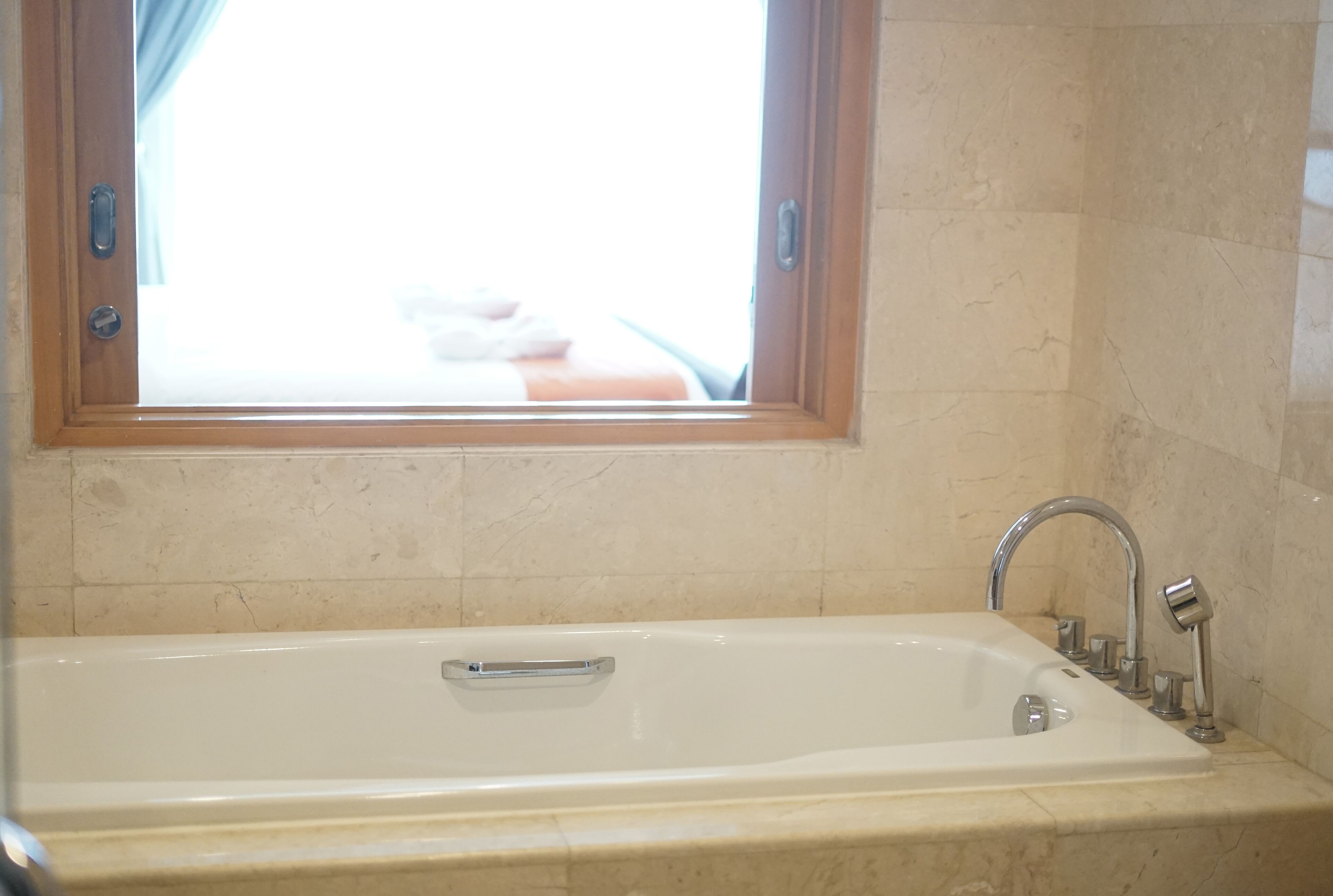 A bathroom with a bathtub, a window, and a sink with a faucet.