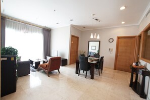 Uma sala de estar moderna com área de jantar, um sofá, uma mesa de centro e uma televisão.