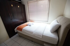 Ein Hotelzimmer mit Bett, Schrank und einem Fenster mit Jalousien.