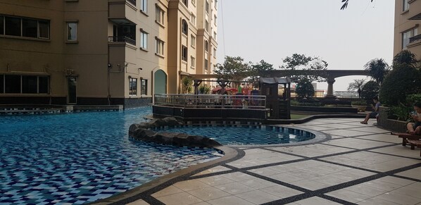 A swimming pool with a tiled pattern, surrounded by a tiled walkway.