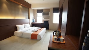 A hotel room with a bed, a desk with a tray of breakfast items, a water dispenser, and a window. - Apatel Silkwood Residences Alam Sutra (Tangerang)